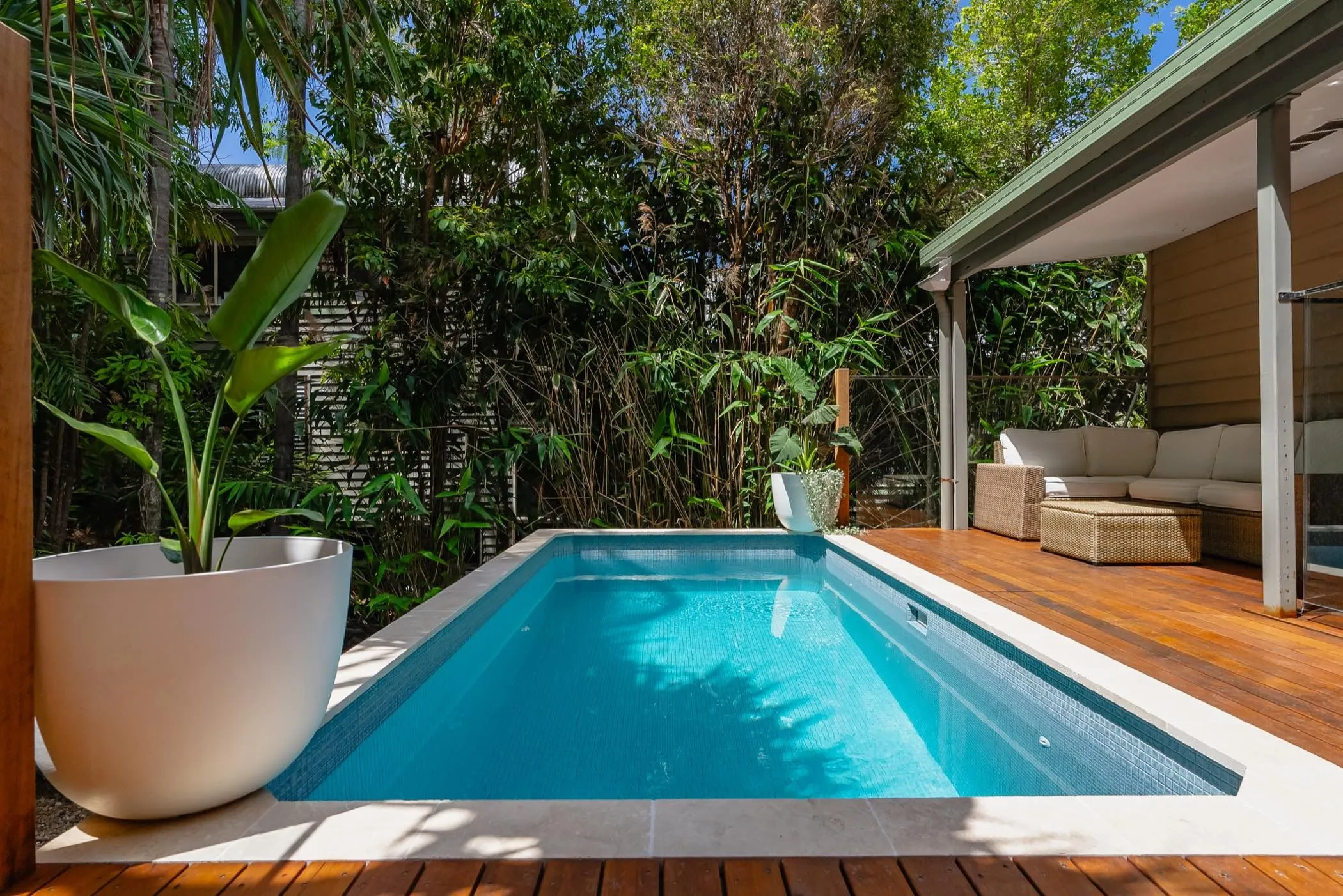 A rectangular tiled plunge pool with timber decking and outdoor lounge seating