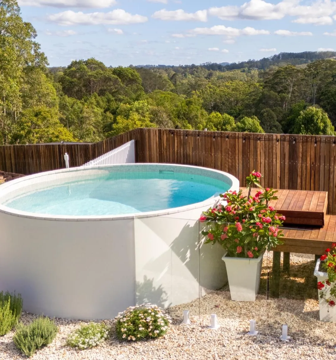 A round, fully tiled precast concrete plunge pool on a garden terrace overlooking bushland